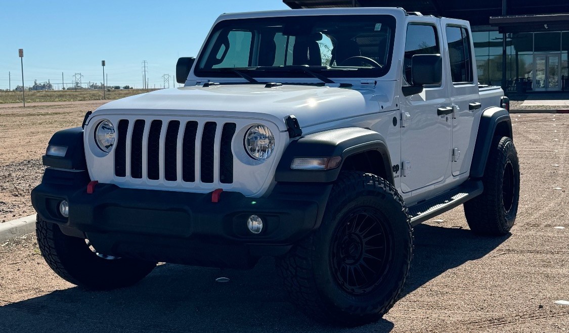 white jeep wrangler on dirt parking lot