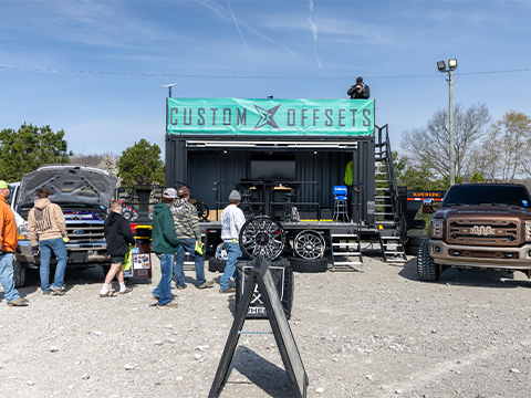 Custom Offsets booth at FP 5.0 with custom built pickup trucks around it