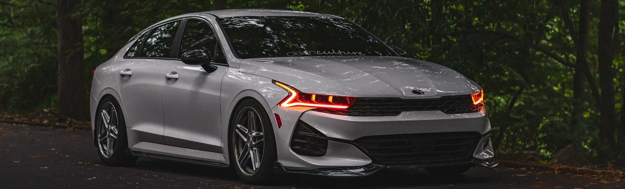 front view of silver kia on forest road