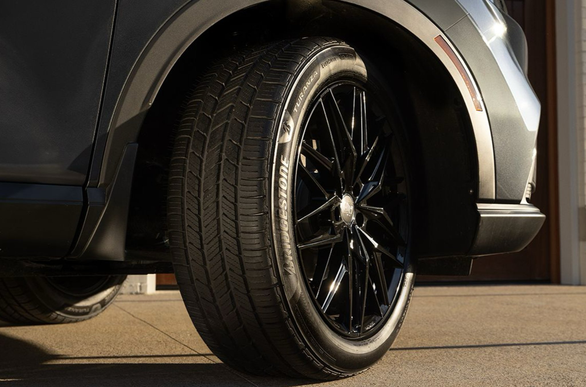Close up of a Bridgestone Turanza tire on a gray SUV with black multi-spoke wheels
