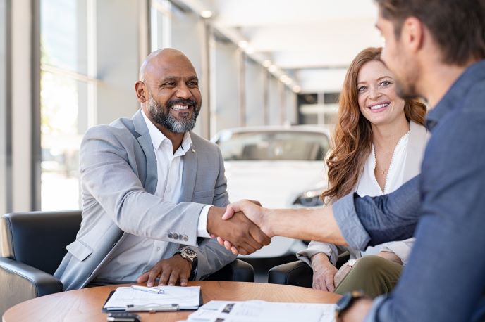 A man shaking hands with someone in a car dealership