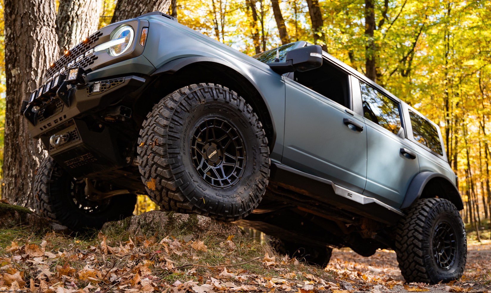 profile view of blue ford bronco climbing rock with anthem valor truck wheel