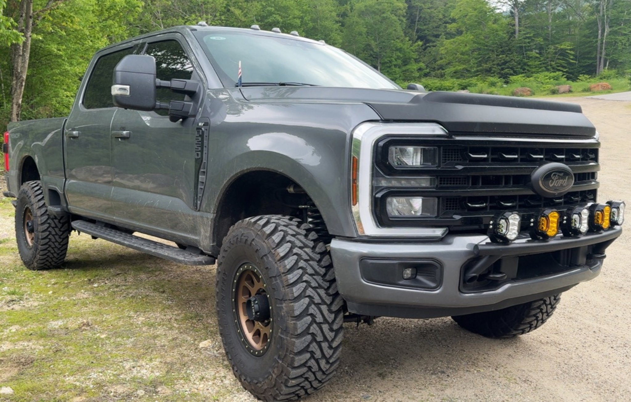 Ford Super Duty pickup with mud-tires and aftermarket wheels on a dirt road