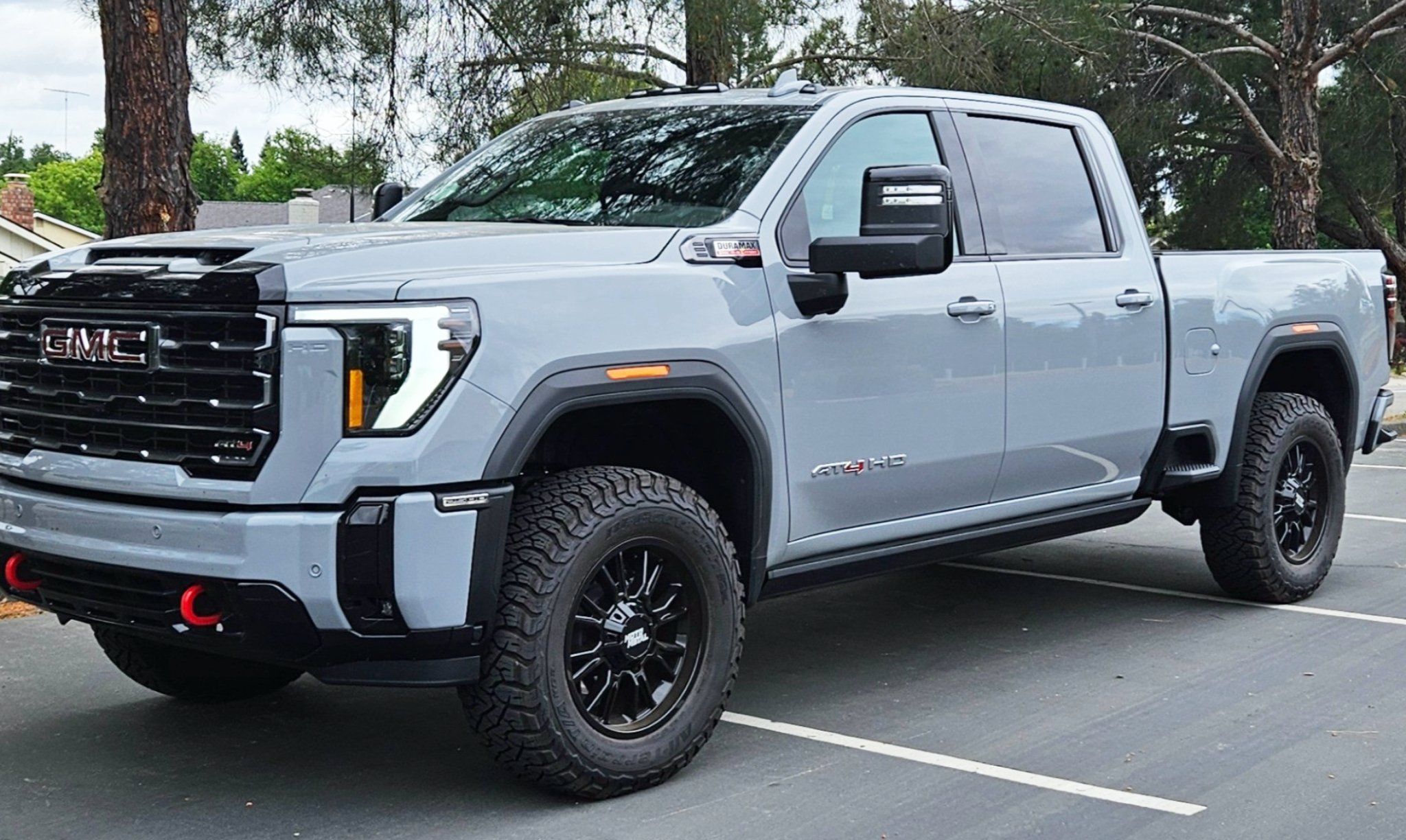 GMC Sierra 2500 with black aftermarket wheels, aggressive, all-terrain tires parked in a lot