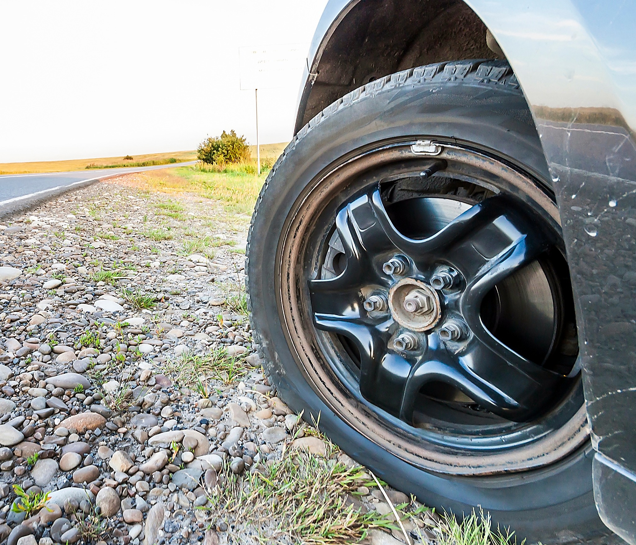 flat tire on a car with black wheels sitting on rocks on the side of the road