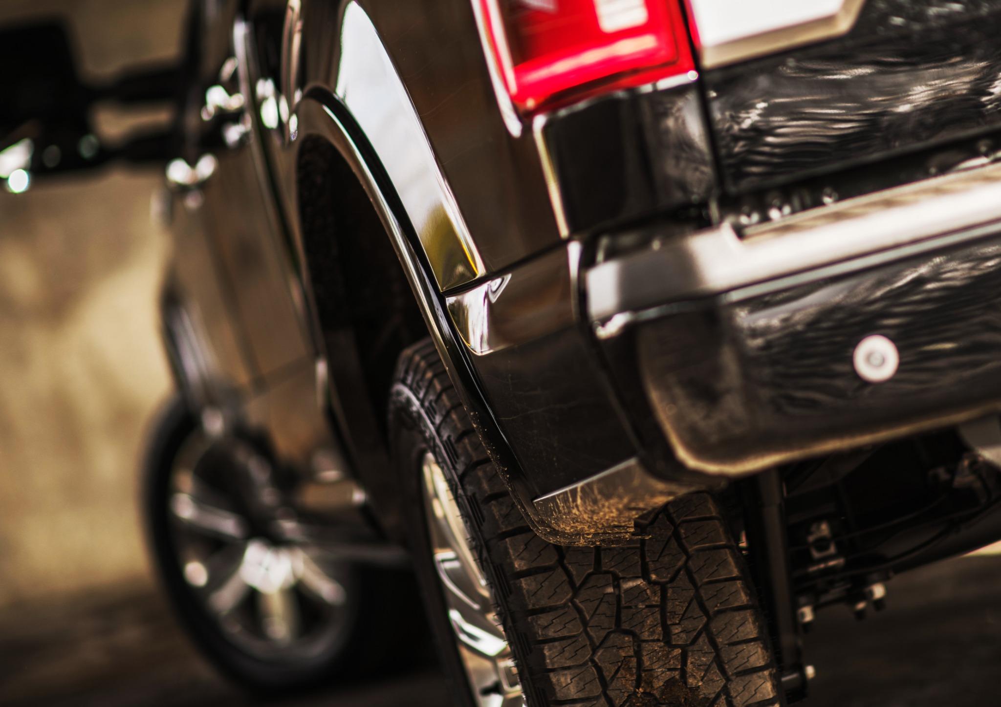 black Ford F-150 pickup truck driving through mud with off-road tires