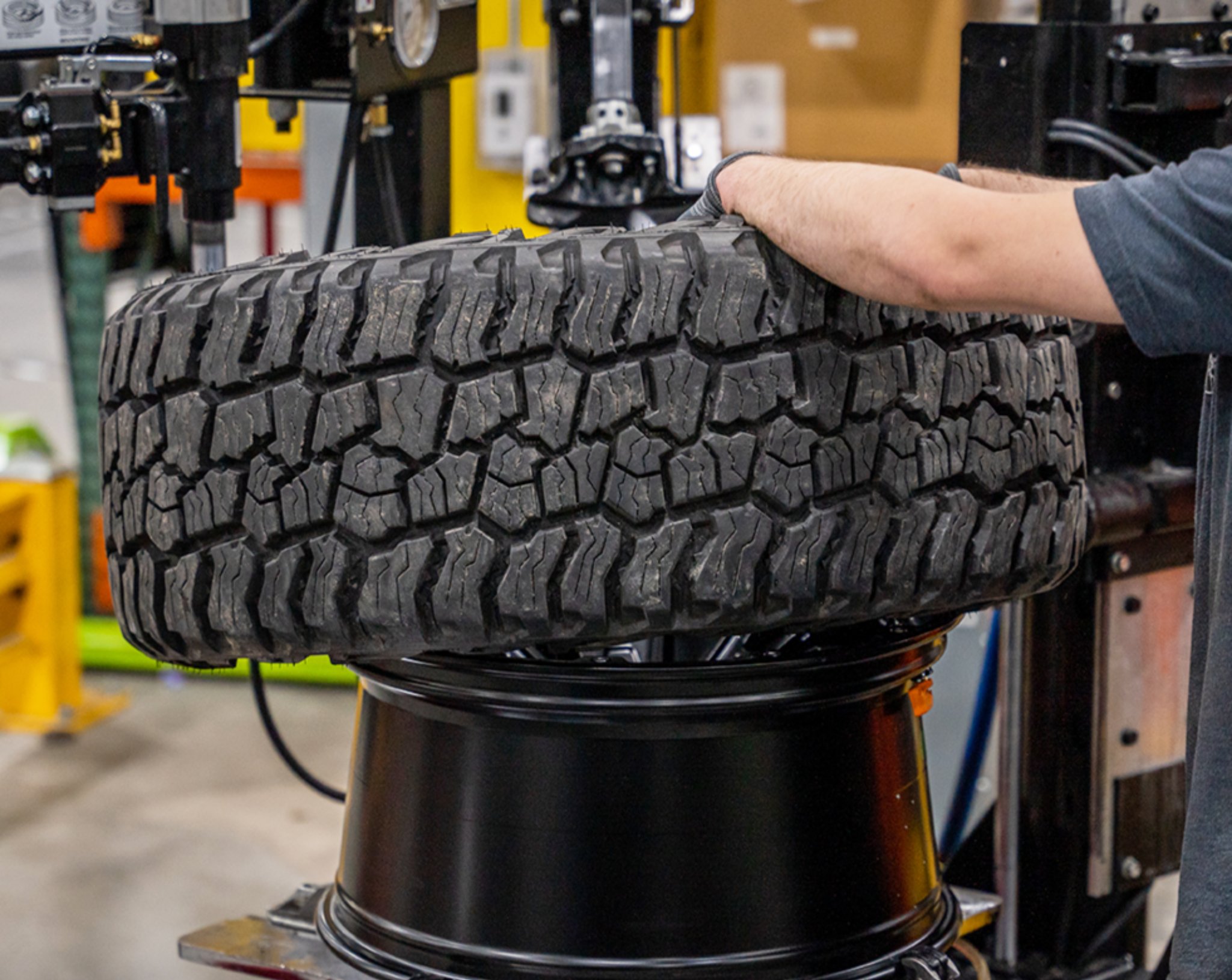 All-terrain tire being mounted on a wheel in a garage