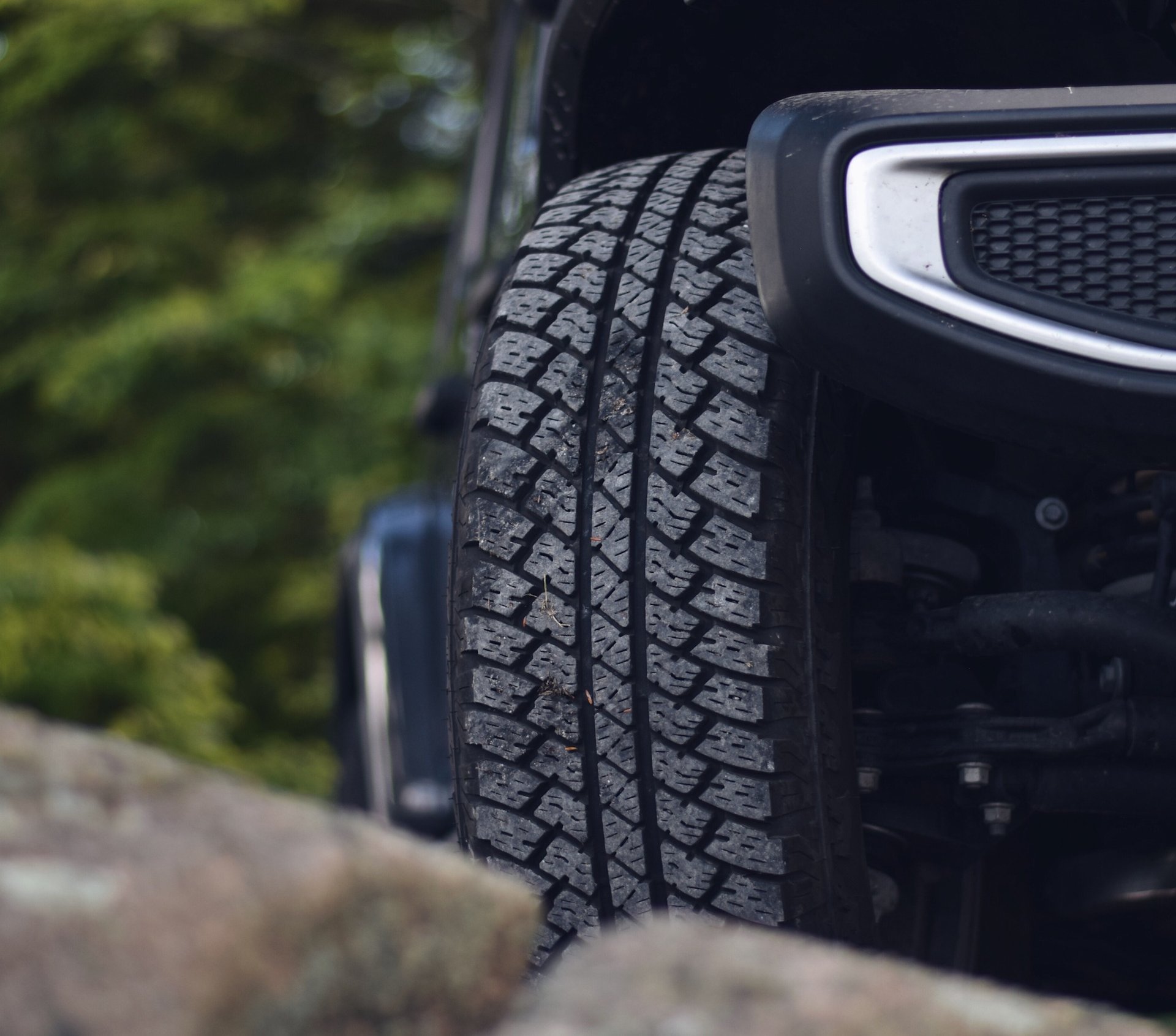 all-terrain tire on a Jeep Wrangler sitting on a rock in an off-road environment