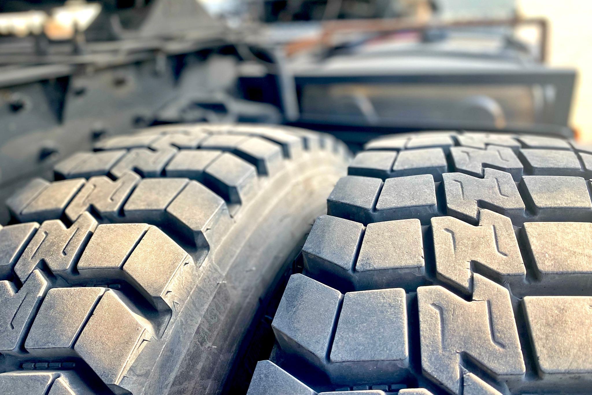 two truck tires sitting side by side outside with the sun shining on them