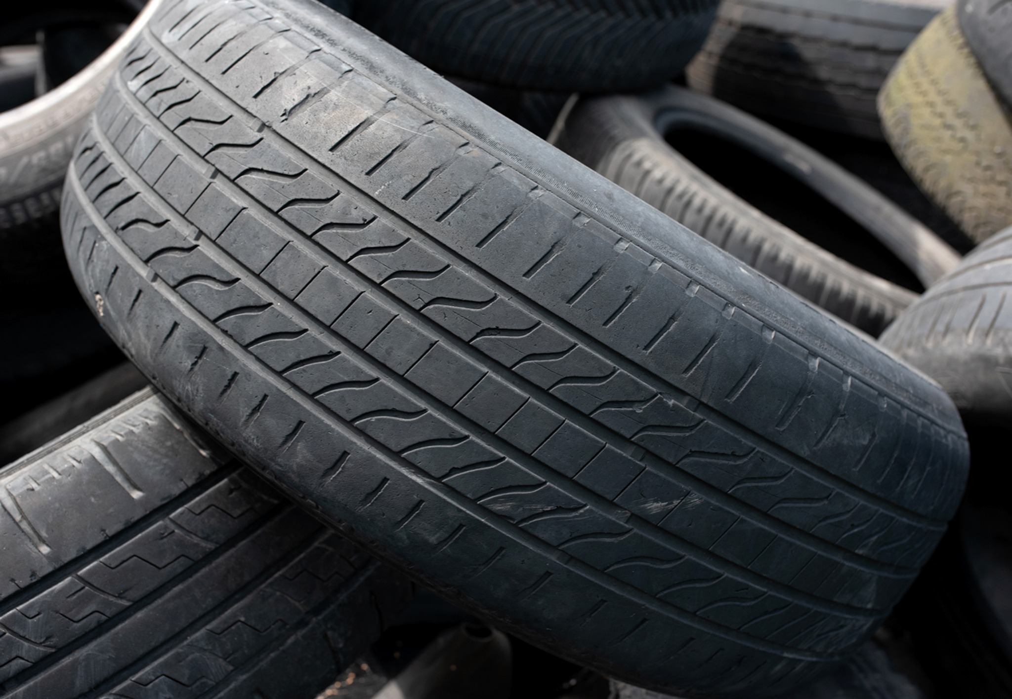 Close up of worn tires stacked together, with visible surface and tread pattern wear