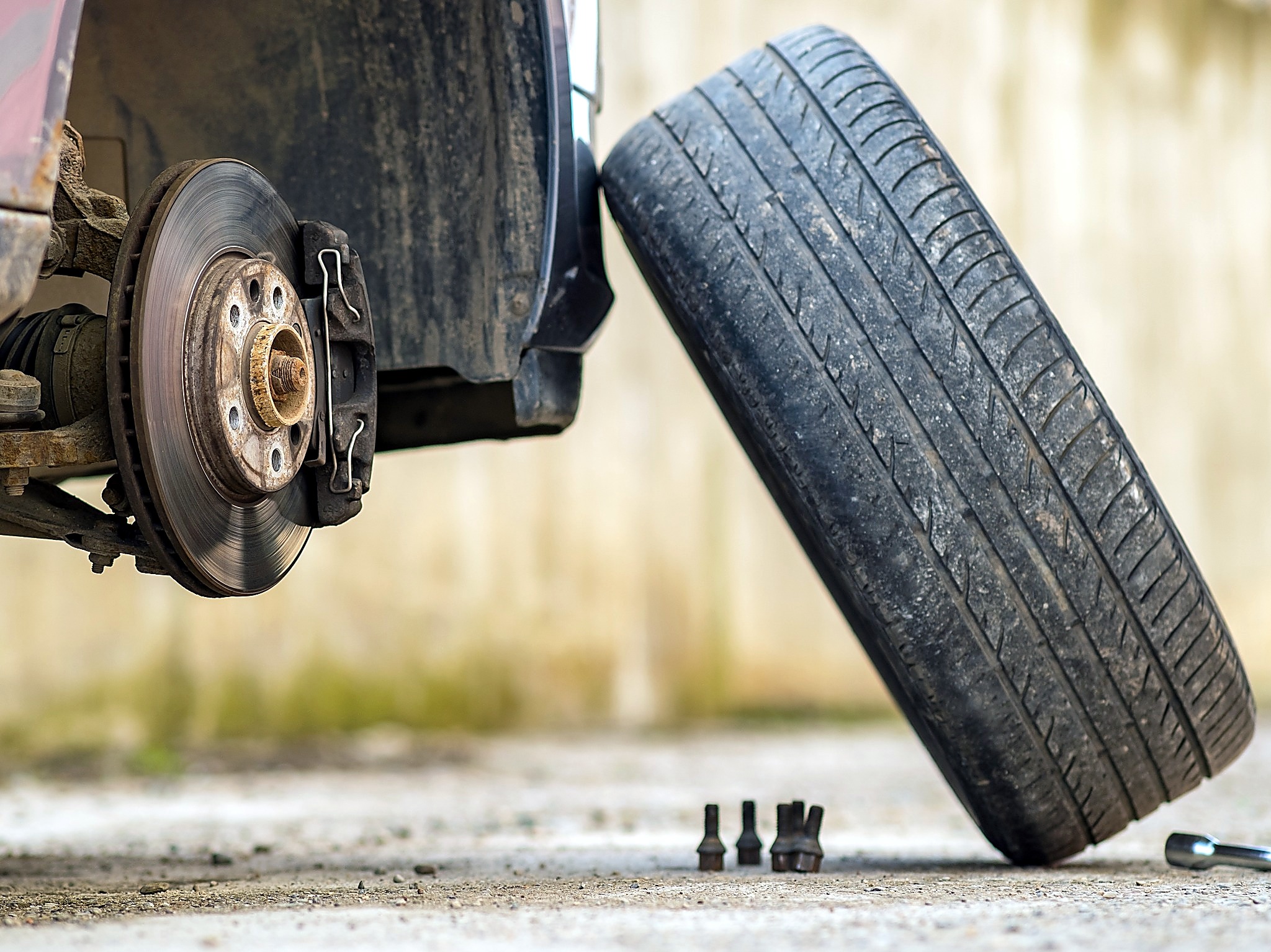 An old, worn-down tire getting replaced, taken off the wheel