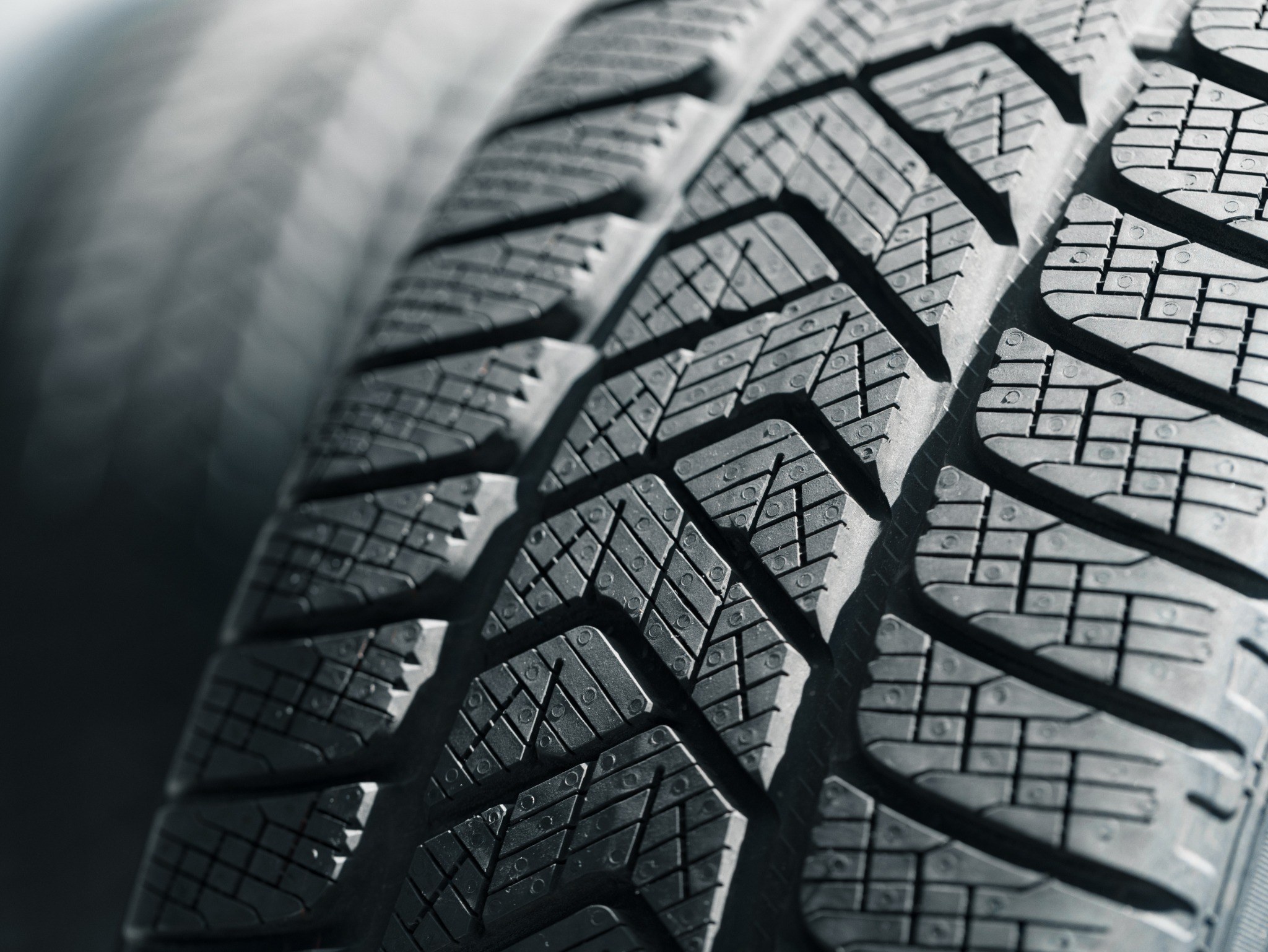 Closeup up of several tire treads of new tires, showing tread pattern and siping
