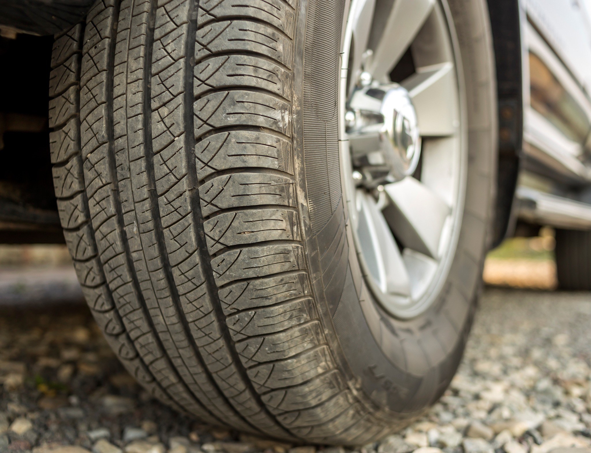 closeup of a car tire tread on a gravel road
