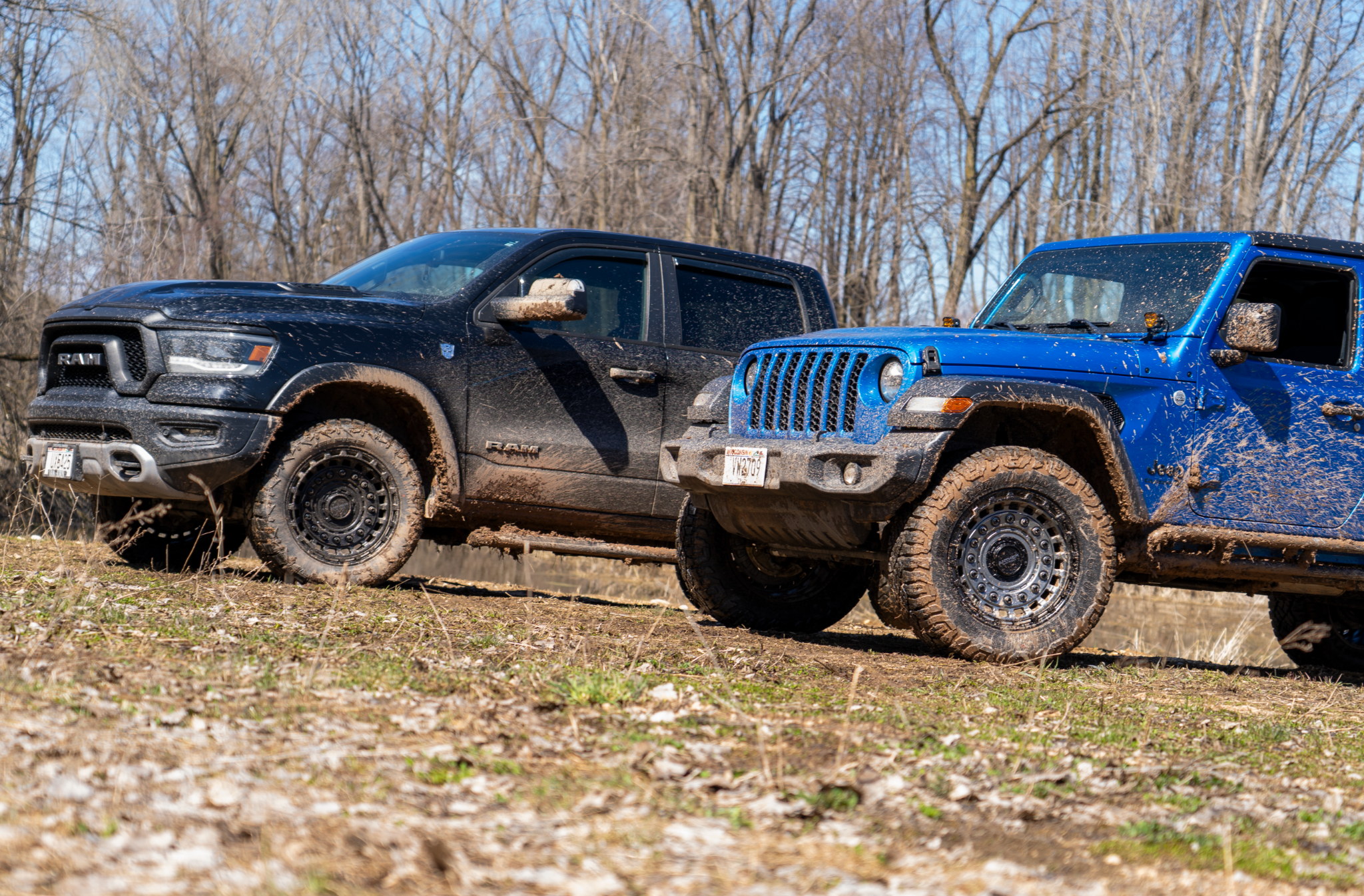 Ram 1500 and Jeep Gladiator both with Anthem Off-Road Mercenary wheels sitting outside covered in mud