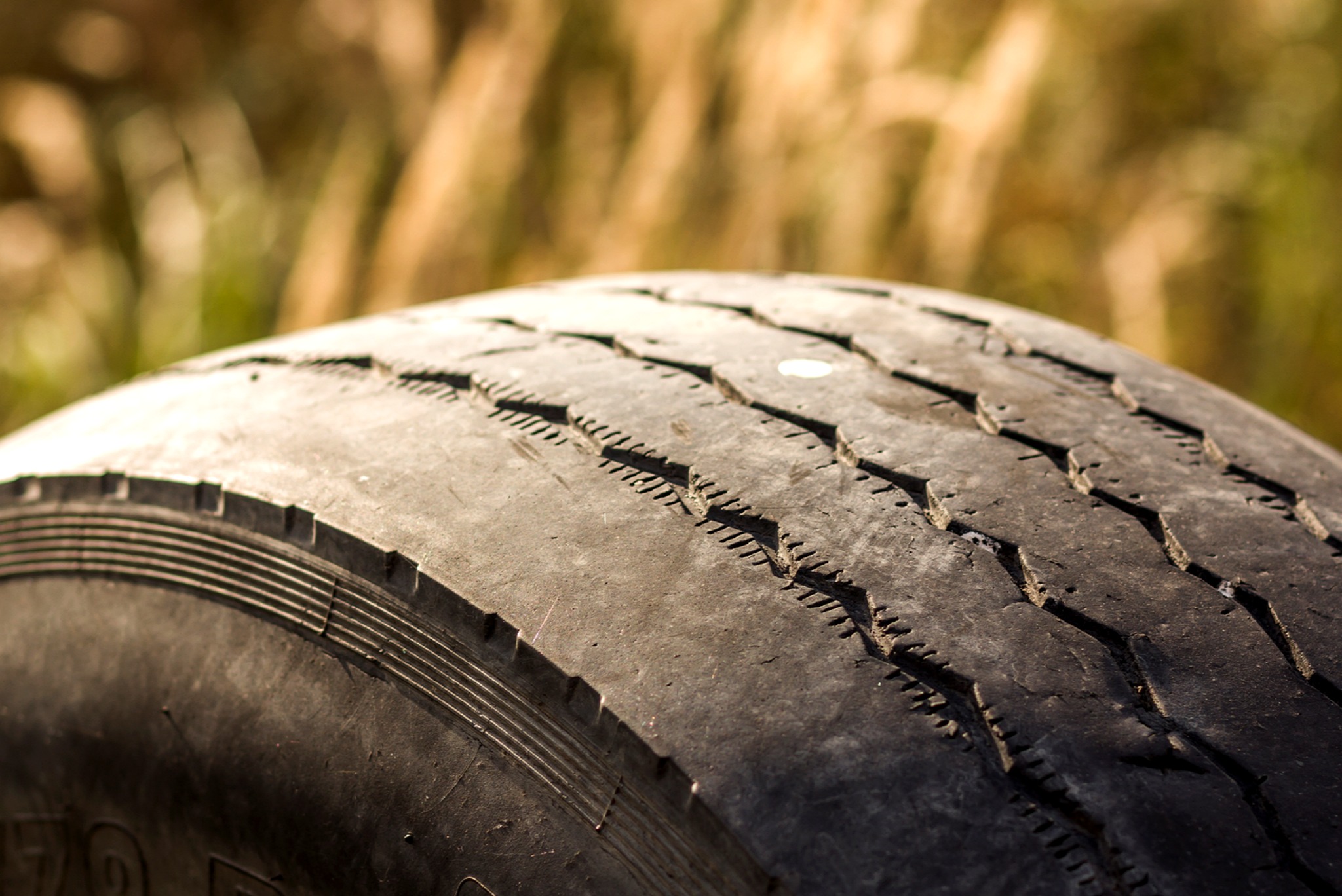 Close up of a heavily worn tire with shallow tread and visible cracking