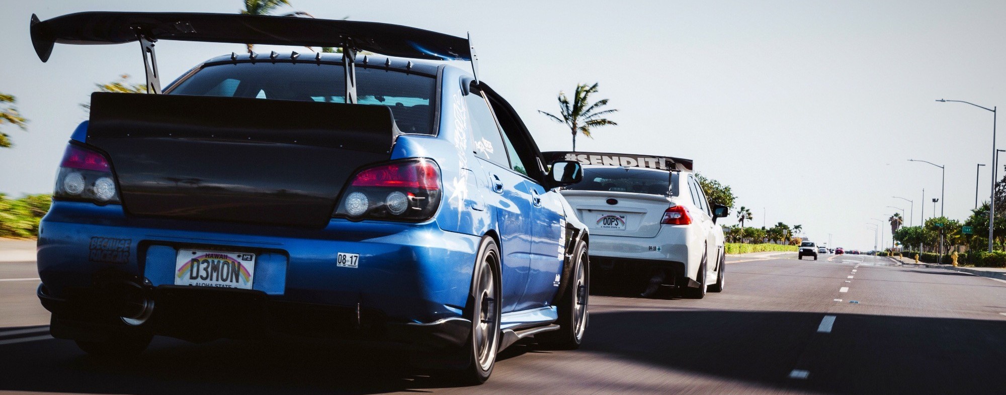 two subaru wrx sti models driving on road