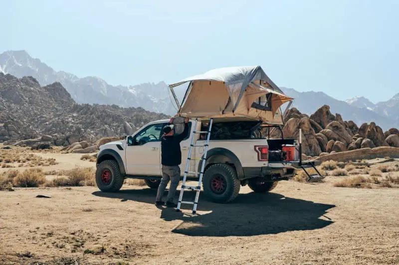 setting up rooftop tent on white off-roader