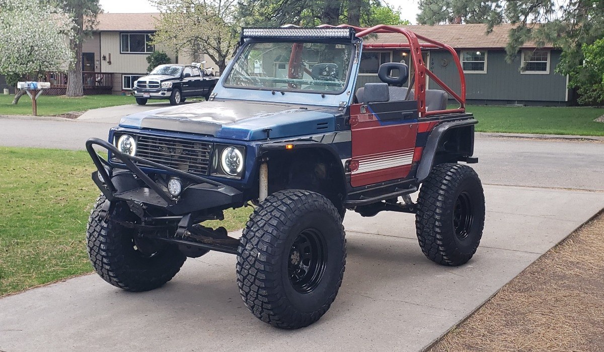 Front view of blue/red suzuki samurai in driveway