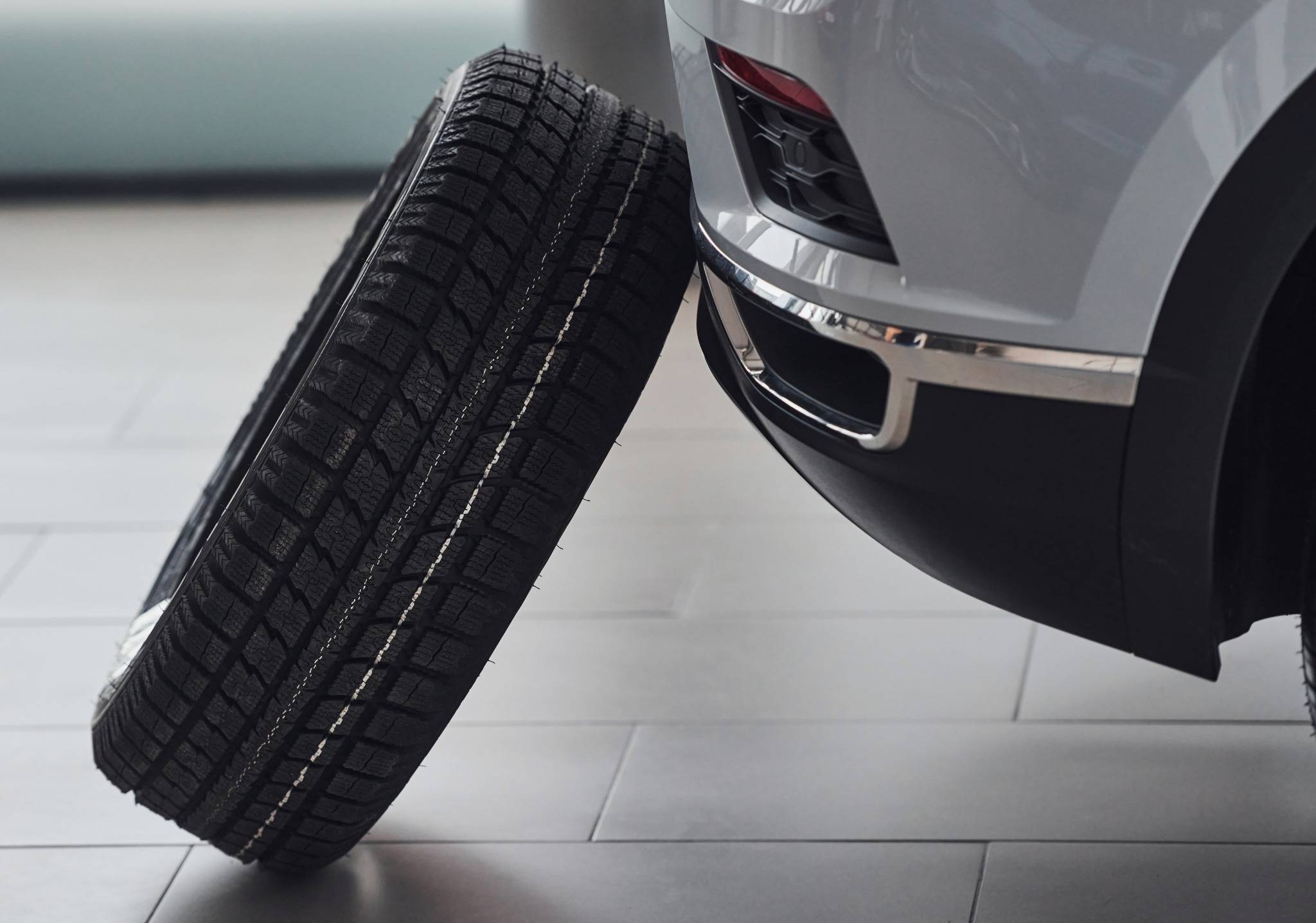 tire propped up against white car