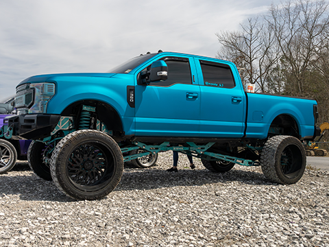 Blue lifted Ford pickup truck with custom wheels and tires at FP 5.0