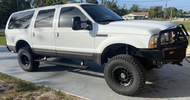profile view of white ford excursion in driveway