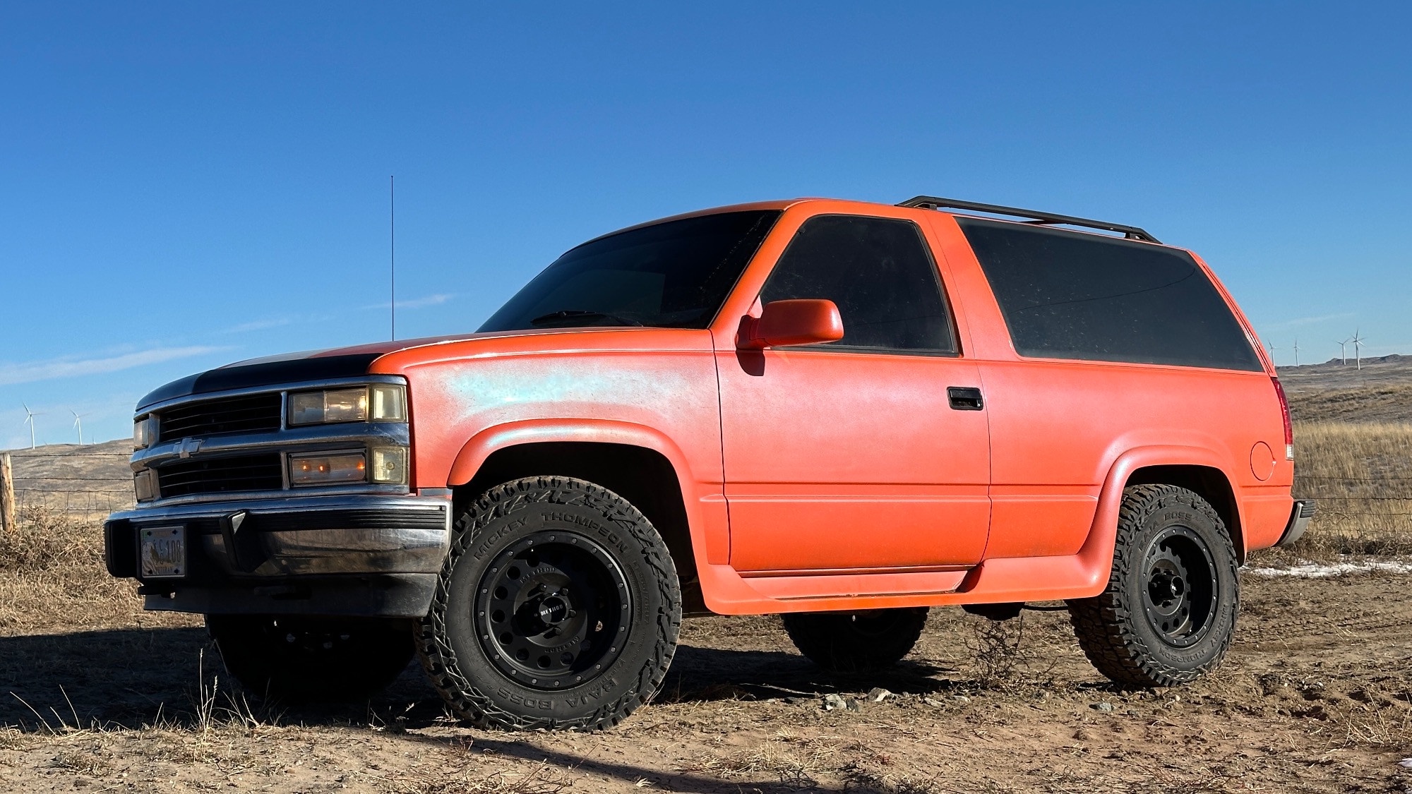 profile view of red chevy blazer in field